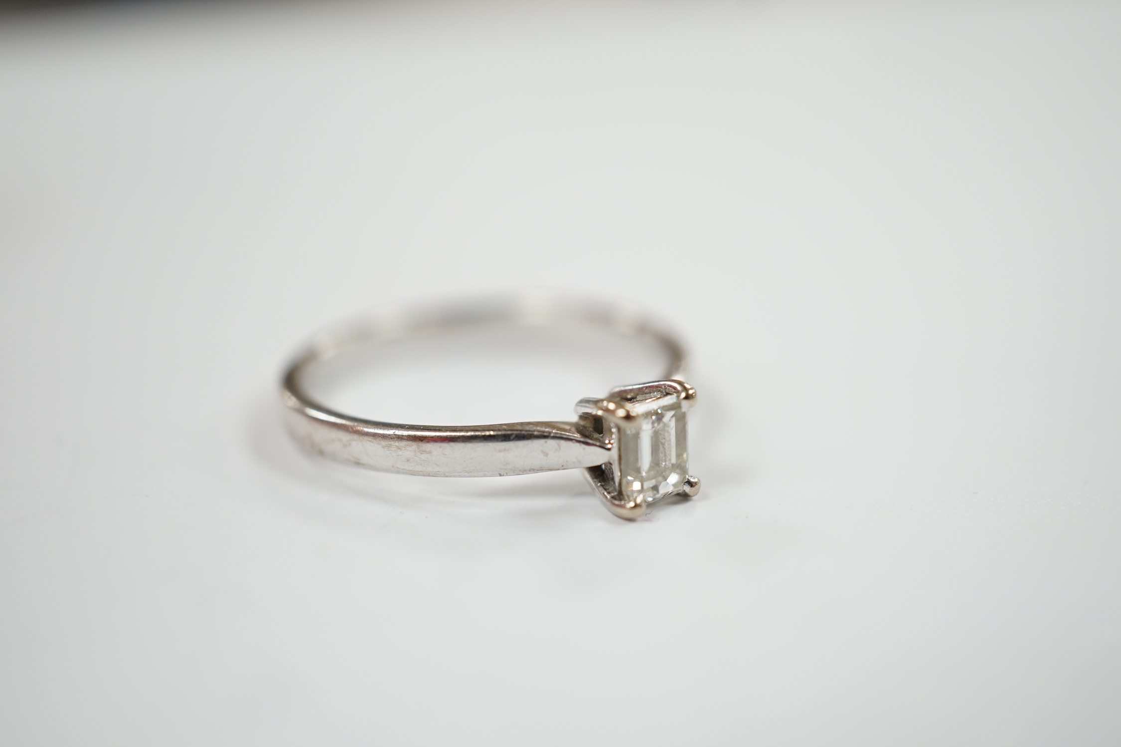 A modern 18ct white gold and solitaire emerald cut diamond set ring, size Q, gross weight 3.4 grams.